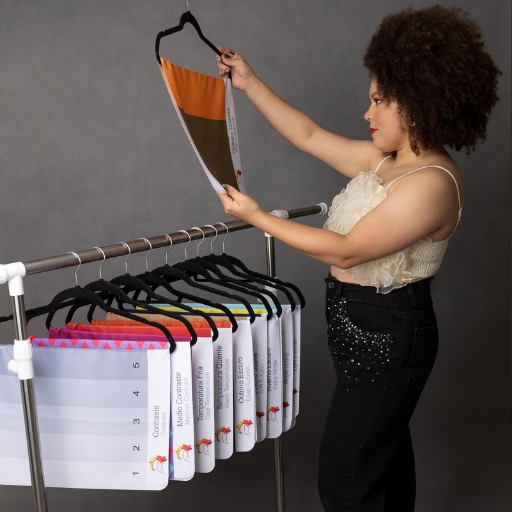 Consultora segurando os tecidos de coloração pessoal que estão em cabides pendurados em uma arara